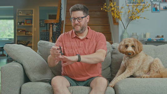 Man on Couch Clipping His Nails Next to His Dog