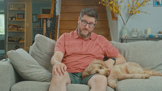 Man on Couch Humming While His Dog Looks On
