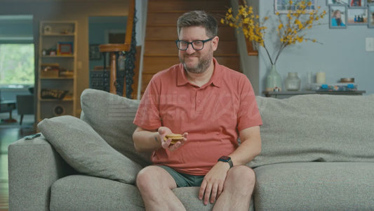Man on Couch Has a Handful of Crackers But Will Not Eat Them