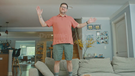 Man Standing on Couch Pretending He is a Tree