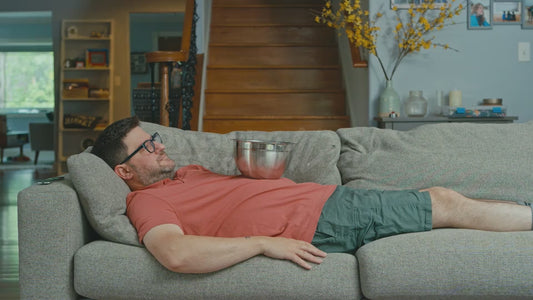 Man Lying on Couch with Large Bowl on His Stomach