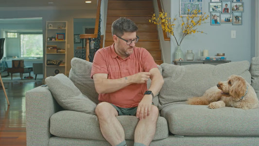 Man on Couch Rolling Cuffs While His Dog Looks On