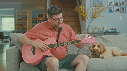 Man on Couch Tuning a Pink Guitar