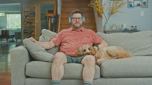 Man on Couch Wearing Headphones with His Dog