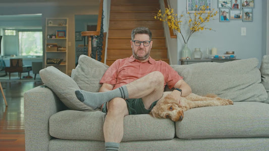 Man on Couch with Sour Countenance While Petting Dog