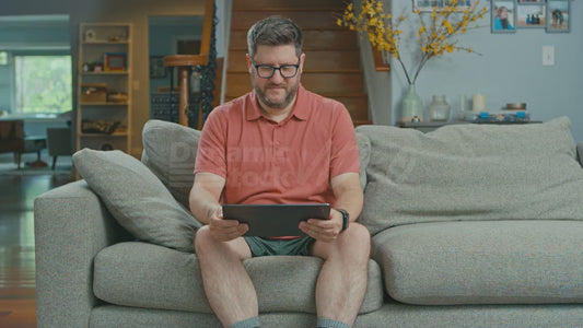 Man on Couch Watching the Moon Landing on His Tablet But Is Not Impressed