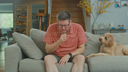 Man on Couch Coughs So Much That He Eventually Passes Out While His Dog Looks On