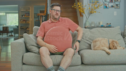 Man on Couch Attempts to Trick Dog into Thinking His is Pregnant By Putting A Pillow Under His Shirt